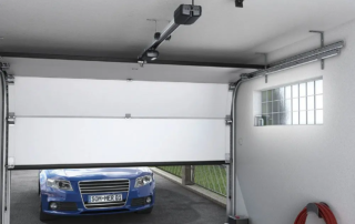 A blue car parked outside a half-open garage door, showcasing a repair service in Appleton.| Badgerland Garage Door Service – Green Bay Garage Door Repair
