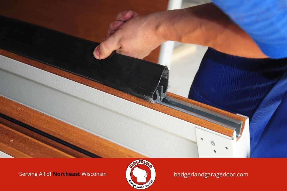 Insulated-vs.-Non-Insulated-Garage-Doors-2 Technician installing weather seal on insulated garage door panel in Northeast Wisconsin by Badgerland Garage Door.