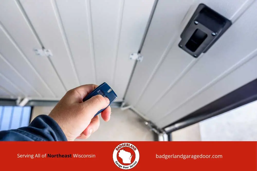 Hand using a remote to open a quiet garage door inside an Appleton attached home.