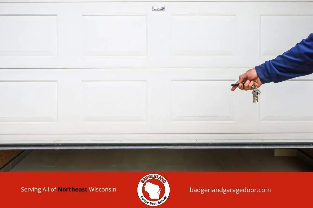 Hand holding remote near a garage door as Badgerland Garage Door provides weatherproofing service for Wisconsin homes in cold weather.