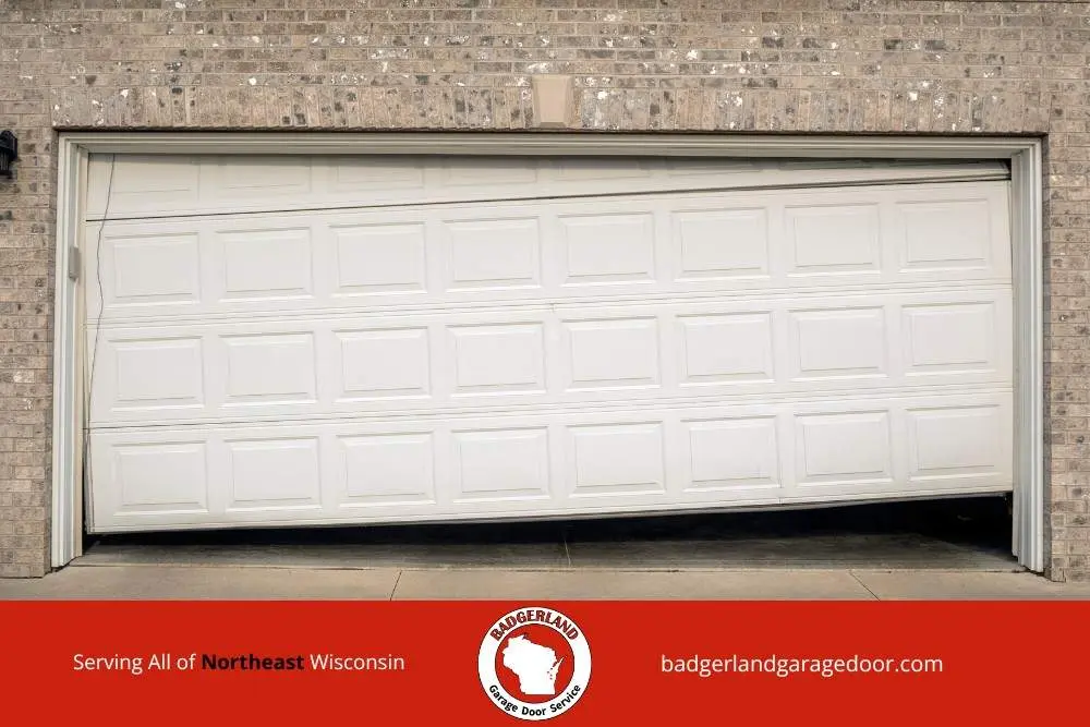 Winter damaged garage door off track at a Wisconsin home, showing issues Badgerland Garage Door provides service to repair.