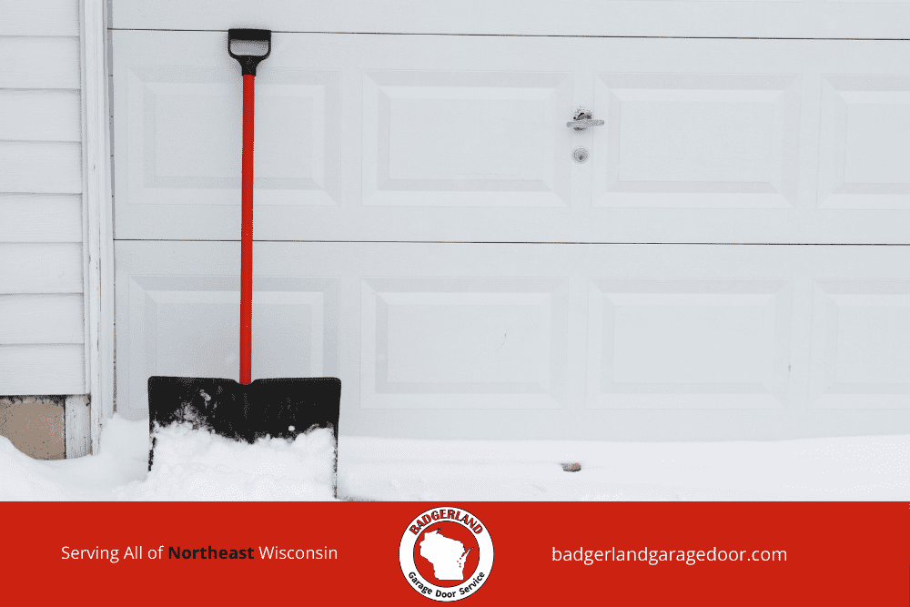 Snow piled against garage door that may cause freezing and sticking in winter. Badgerland Garage Door Service.