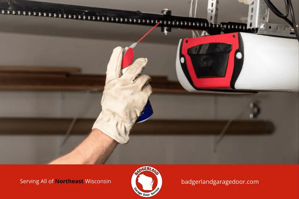 Homeowner clearing snow from garage door to improve winter safety and protect equipment. Badgerland Garage Door Service.