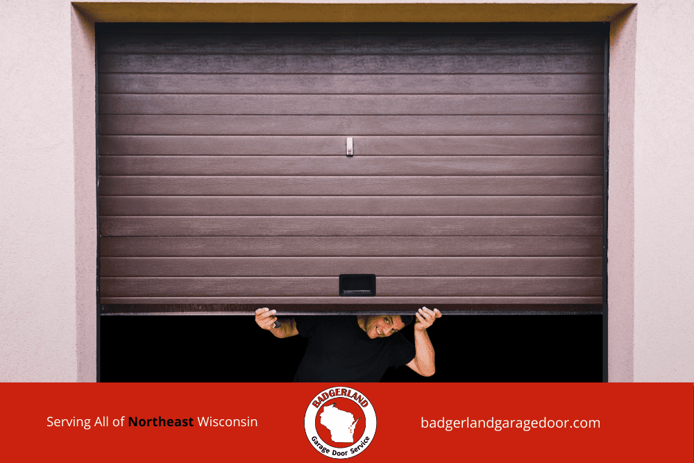 A person peeks under a brown garage door, showcasing Garage Door Repair services in Wisconsin.| Badgerland Garage Door Service – Green Bay & Appleton Garage Door Repair