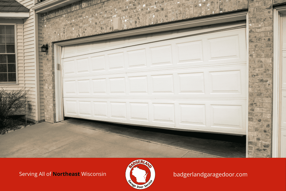 White garage door halfway open, needing repair service in Wisconsin, highlighting garage door repair expertise.| Badgerland Garage Door Service – Green Bay & Appleton Garage Door Repair