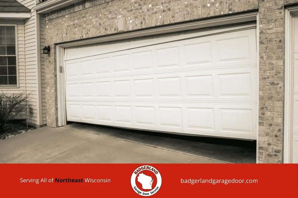 Why Garage Door Balance Matters More in Wisconsin Winters-2 White garage door halfway open, needing repair service in Wisconsin, highlighting garage door repair expertise.| Badgerland Garage Door Service – Green Bay & Appleton Garage Door Repair