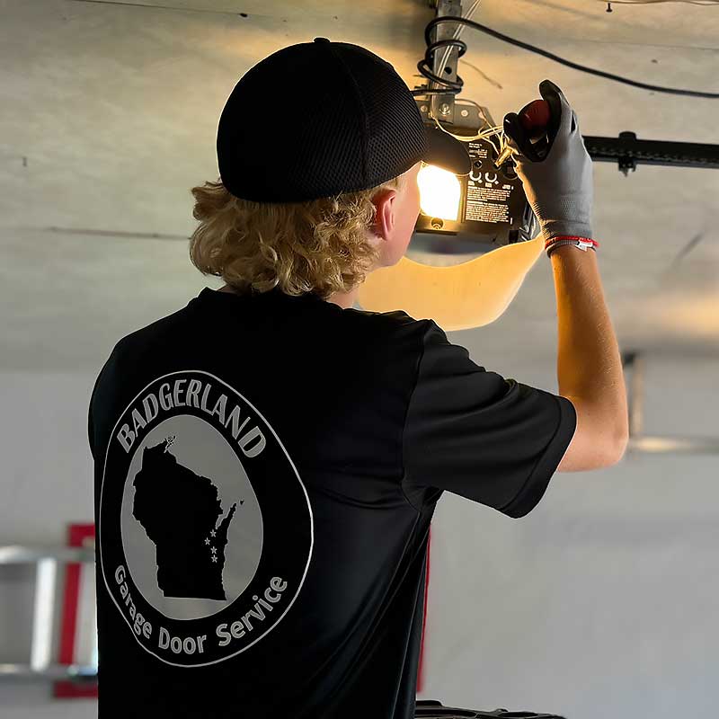 Technician repairs a garage door opener, wearing a Badgerland shirt, serving Green Bay and Appleton homeowners.| Badgerland Garage Door Service – Green Bay Garage Door Repair