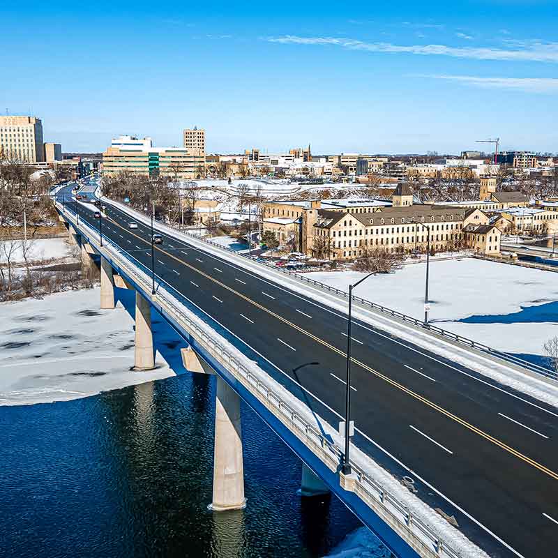 A snow-covered Appleton cityscape with a bridge over a frozen river under a clear blue sky.| Badgerland Garage Door Service – Green Bay Garage Door Repair