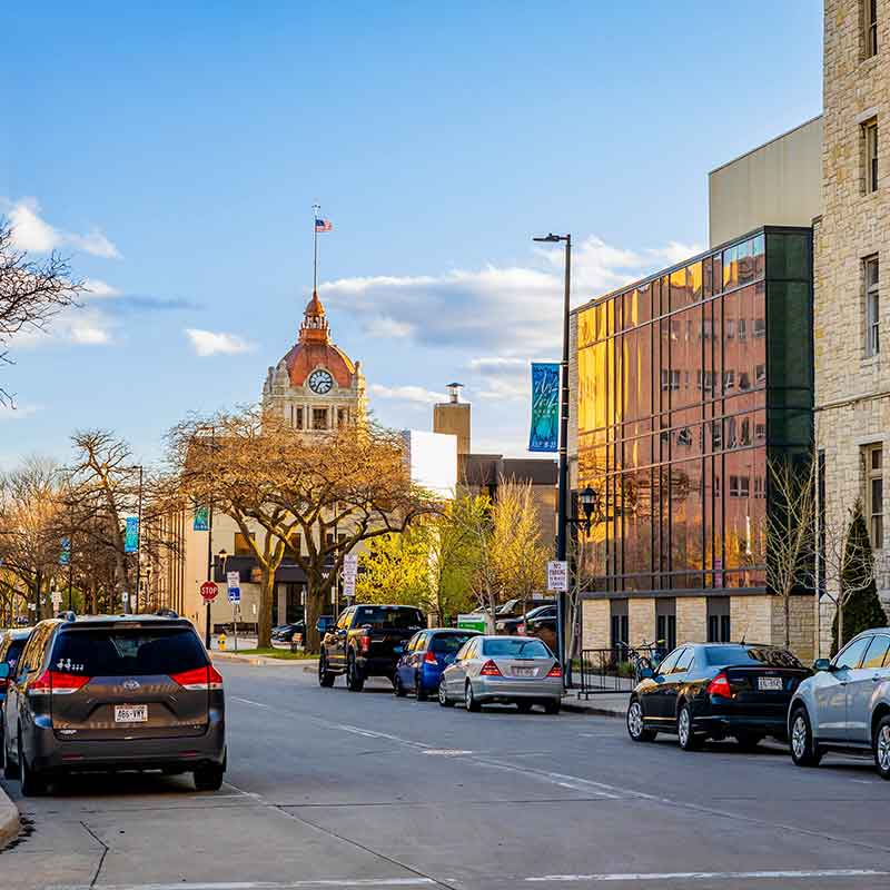Street view in Appleton with cars parked alongside buildings under a blue sky.| Badgerland Garage Door Service – Green Bay Garage Door Repair
