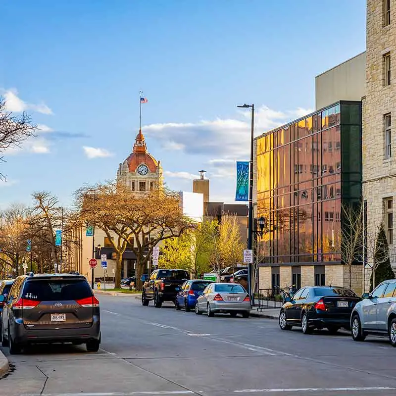 Street view in Appleton with cars parked alongside buildings under a blue sky.| Badgerland Garage Door Service – Green Bay Garage Door Repair